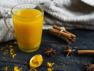 turmeric tea with cinnamon and ginger on wooden background