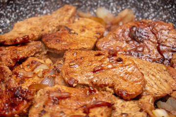 Cooking fryed meat on the pan with onion close up