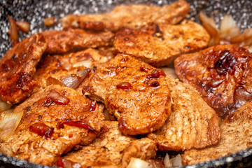 Cooking fryed meat on the pan with onion close up