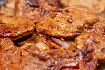 Cooking fryed meat on the pan with onion close up