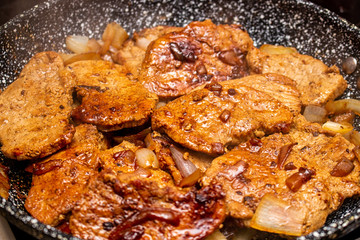 Cooking fryed meat on the pan with onion close up
