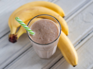 Banana smoothie on wooden white background, healthy food