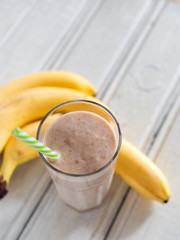 Banana smoothie on wooden white background, healthy food