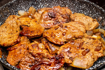 Cooking fryed meat on the pan with onion close up