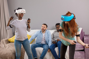 Now it is girl s turn to play 3D reality tennis game on virtual tennis court, interracial female couple female in VR headset experience exciting emotions.
