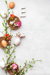 Easter background with chicken and quail eggs,  bunny ear napkin and  spring blossom branch on the textured surface, top view, copy space
