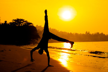 silhouette of young man standing on his hands taken in sri-lanka on the sunrise