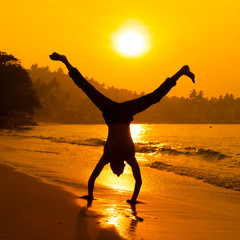 silhouette of young man standing on his hands taken in sri-lanka on the sunrise
