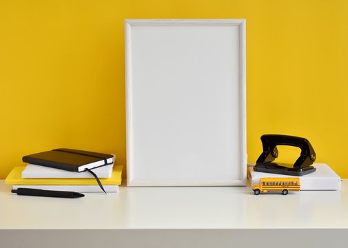Student work place with black and yellow office supplies, books, school bus toy, white frame mock up.