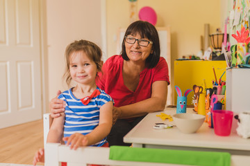 Fototapeta premium Grandmother and granddaughter doing handycraft together in nursery
