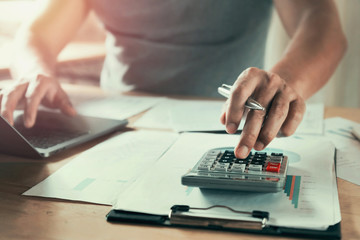 businessman working on desk using calculator to calculate data of finance in office