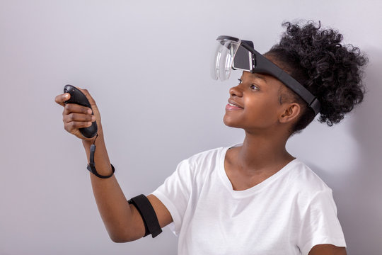Curious smart african american female teenager with mobile virtual reality headset and joystick makes settings for making virtual tour to Austria