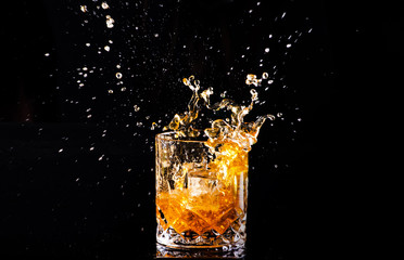 shot of whiskey with splash on black background, brandy in a glass