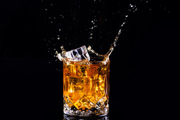 shot of whiskey with splash on black background, brandy in a glass