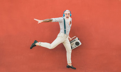 Senior crazy man jumping and listening music outdoor