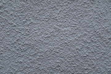 A close up photo of an exterior textured wall painted gray, surface with stucco daub, great for background