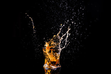 shot of whiskey with splash on black background, brandy in a glass