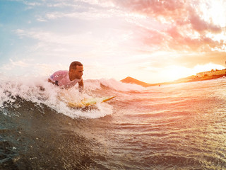 Male athlete surfing at sunset