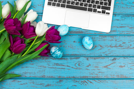 Easter eggs, mockup laptop and bouquet of tulips.