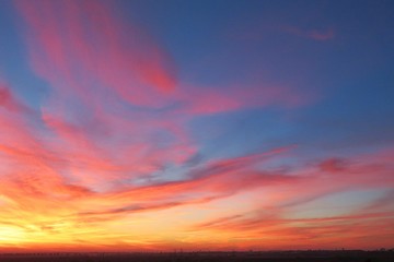 Beautiful fiery pink sunset background over the city, red flame in blue sky at sunset