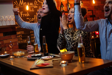 Group of friends watching tv in a cafe behind bar counter