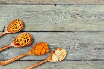 Mix of snacks : pretzels , crackers , chips  and nachos on the table