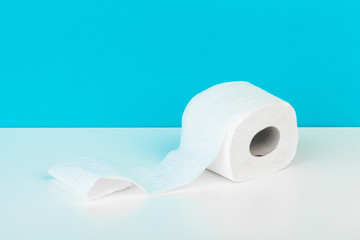Toilet paper isolated on white table with blue background. Cleaning concept product