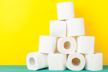 Toilet paper rolls stacked against yellow paper background
