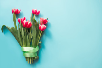 Bouquet of red tulip on pastel blue. Mothers Day. Top view with copy space.