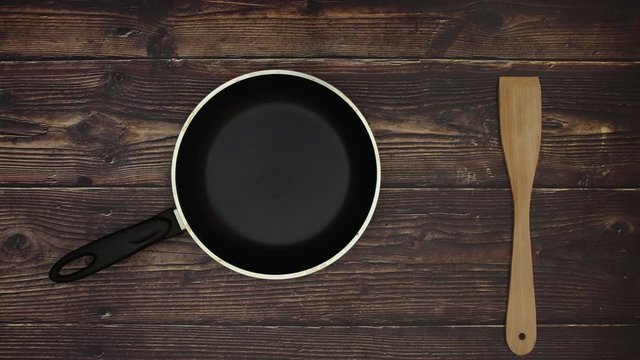 Pan eggs and wooden spoon on wooden background - Stop motion