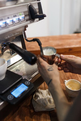 Barista whips milk on a professional coffee machine