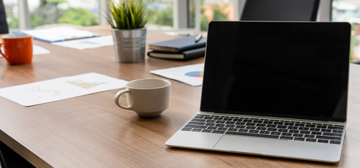 Laptop computer with opened lid on table in meeting room of office workspace.