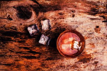 whiskey with ice cubes on wooden background