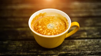 Fotobehang A yellow cup of tasty coffee, on rustic wooden table background © The Len
