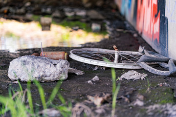 Old broken bicycle wheel and rusty spray cans