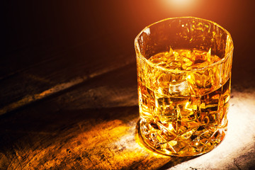 whiskey with ice cubes on wooden background