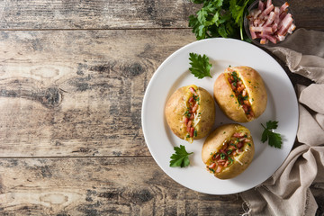 Stuffed potatoes with bacon and cheese on plate on wooden table. Top view. Copyspace