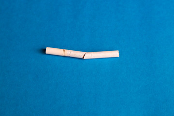 A white filter cigarette is broken in half. A white filter cigarette is broken in half.