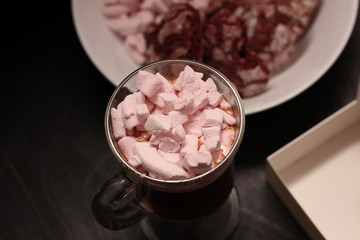 hot drink in a glass cup with pink marshmallows and white box with a transparent cover in the form of heart with cookies