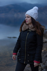 Young girl facing a lake during a cloudy day