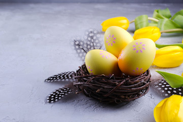 Easter concept - Decorative willow nest with decorative eggs, feather on white background. Copyspace for text. flat lay