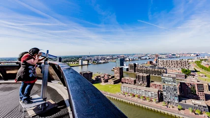 Zelfklevend Fotobehang Woman observing through a telescope the city of Rotterdam in the Netherlands Holland © Emile