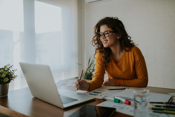 Successful female graphic designer watching tutorial about creative ideas at laptop computer during...