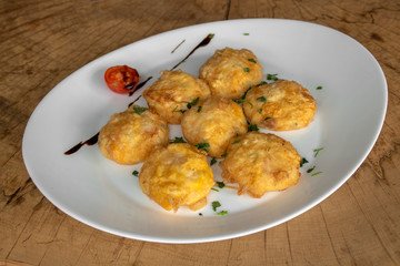 Breaded balls. With white and yellow cheese, flour, egg. Garnished with cherry tomatoes, parsley and balsamic dressing.