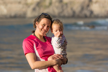 Fototapeta na wymiar Mother and daughter posing on sandy beach.