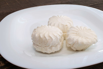 fresh white marshmallow in a white ceramic plate on brown wooden table
