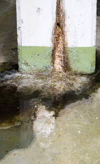water damage in concrete construction with calcium and rust deposits and puddles