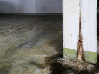 water damage in concrete construction with calcium and rust deposits and puddles