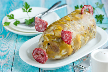 Russian dish holodets, headcheese, pork meat jelly, aspic in bottle shaped funny pig decorated with salami sausage and black pepper