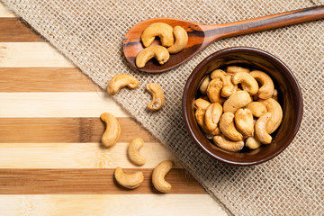 Toasted chestnuts inside brown ceramic and wooden spoon on bamboo wooden background.